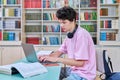 Young male student sitting with laptop with books in college library Royalty Free Stock Photo