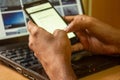 Young male student typing on phone sitting at wooden table. View of business man hands using mobile phone at office desk Royalty Free Stock Photo