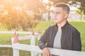 Young male student by the wooden fence thinking about his future, happy for his achievements Royalty Free Stock Photo