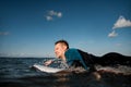 Young male surfer in wetsuit lying on surfboard and waiting for wave to stand up Royalty Free Stock Photo