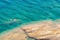 Young male swimming and snorkeling around rocky shore looking through the clear turquoise sea water