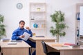 Young male teacher checking notes in the classroom