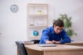 Young male teacher checking notes in the classroom