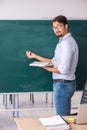 Young male teacher in front of blackboard