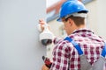 Young Male Technician Installing Camera On Wall