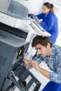 Young male technician repairing digital photocopier machine