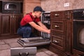 Young Male Technician Repairing Dishwasher In Kitchen Royalty Free Stock Photo