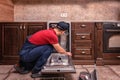 Young Male Technician Repairing Dishwasher In Kitchen Royalty Free Stock Photo