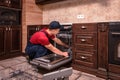 Young Male Technician Repairing Dishwasher In Kitchen Royalty Free Stock Photo