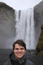 Young male tourist aged 20-25 poses in front of skogafoss waterfall in Iceland. Iceland has become a popular tourist Royalty Free Stock Photo