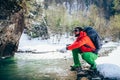 Young male tourist fillings water into the bottle from a river in the mountains.