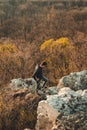 Young male tourist walking on the rocks with perfect view on valley and trees. Man adventurer standing on the rocks over the Royalty Free Stock Photo