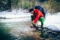 Young male tourist washes his face with river water in the mountains.