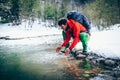 Young male tourist washes his face with river water in the mountains.