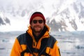 Young Male Tourist with yellow jacket in Antarctica smiling. Icebergs in background. Hiking with backpack in mountains Royalty Free Stock Photo