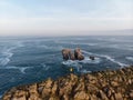 Tourist standing at Urro del Manzano rock formation natural arch bridge in Liencres Arnia Santander Cantabria Spain