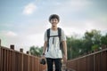 Young male traveler photographer smiling walking on wooden bridge with backpack and holding a camera Royalty Free Stock Photo