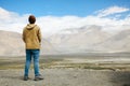 Young male traveler standing on the sand cliff, thinking about or looking forward to something in Leh, Ladakh,India
