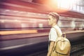 Young male traveler in station, with blurry train speeding