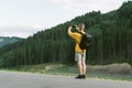 Young male traveler in yellow sweatshirt taking photo on smartphone of mountain forest landscape. Back view of tourist man using Royalty Free Stock Photo