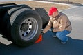 Young male truck driver chocking wheels for safety