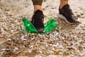 Young male volunteer stands on plastic garbage on the ocean coast. A man collects waste on the seaside to save ecology and protect Royalty Free Stock Photo