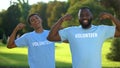 Young male volunteers showing arm muscles, strength gesture, teamwork support Royalty Free Stock Photo