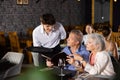 Young male waiter takes order from elderly couple in restaurant Royalty Free Stock Photo