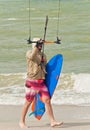 Young male walkingalong shoreline with kiteboard