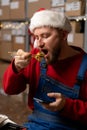 Young male warehouse worker having lunch at workplace eating delicious fresh sushi rolls, food delivery concept. Royalty Free Stock Photo