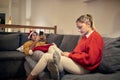 Young male wearing santa hat using cell phone on christmas laying on sofa with his girlfriend sitting, also using mobile phone