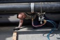 A young male worker cuts a large diameter steel pipe on high-precision equipment by means of an autogen