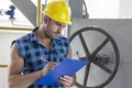 Young male worker writing on clipboard by large valve in industry Royalty Free Stock Photo