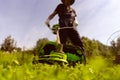 man is actively mowing a lawn with a lawn mower in his beautiful floral garden, Royalty Free Stock Photo