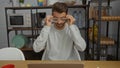 Young man adjusting glasses indoors at a stylish office with modern decor, suggesting a dynamic and focused workspace environment Royalty Free Stock Photo