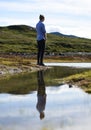 Young man admiring the landscape and the reflection view on the river surface, Valdres, Norway Royalty Free Stock Photo