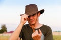 Young man affected farmer in cowboy hat at agricultural field holding tablet. Male on nature green background, outdoors Royalty Free Stock Photo