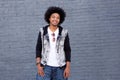 Young man with afro smiling standing in front of gray wall