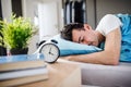 Young man with alarm clock in bed at home, sleeping. Royalty Free Stock Photo