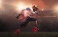 Young man american football player at stadium in motion in explosion of colored neon powder. Action, activity, sportlife