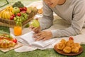 Young man with apples lies on green grass and reads book. Royalty Free Stock Photo