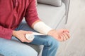 Young man applying bandage on injured arm at home. First aid Royalty Free Stock Photo