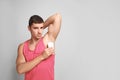 Young man applying deodorant to  on light background. Space for text Royalty Free Stock Photo