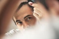 Young man applying lotion for alopecia and hair loss treatment Royalty Free Stock Photo