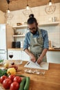 Young man in apron peeling, cutting garlic while preparing dinner, standing in the kitchen. Cooking at home concept Royalty Free Stock Photo
