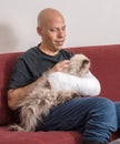 Young man with an arm cast petting his cat Royalty Free Stock Photo