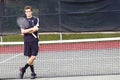 Young man, arms crossed, tennis racket