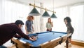 Man arranging balls for multiethnic friends playing pool in game room Royalty Free Stock Photo