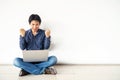 Young man asian sitting on the floor with using computer laptop happy excited with big smile posing isolated over white wall Royalty Free Stock Photo