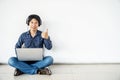 Young man asian sitting on the floor with using computer laptop listening nice music is happy with big smile doing ok sign, thumb Royalty Free Stock Photo
